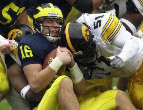 Michigan quarterback John Navarre (16) is sacked by Iowa's Howard Hodges, left, and Fred Barr (51) in the second quarter Saturday, Oct. 26, 2002, in Ann Arbor, Mich. Navarre was sacked five times in Michigan's 34-9 loss to Iowa. (AP Photo/Carlos Osorio)